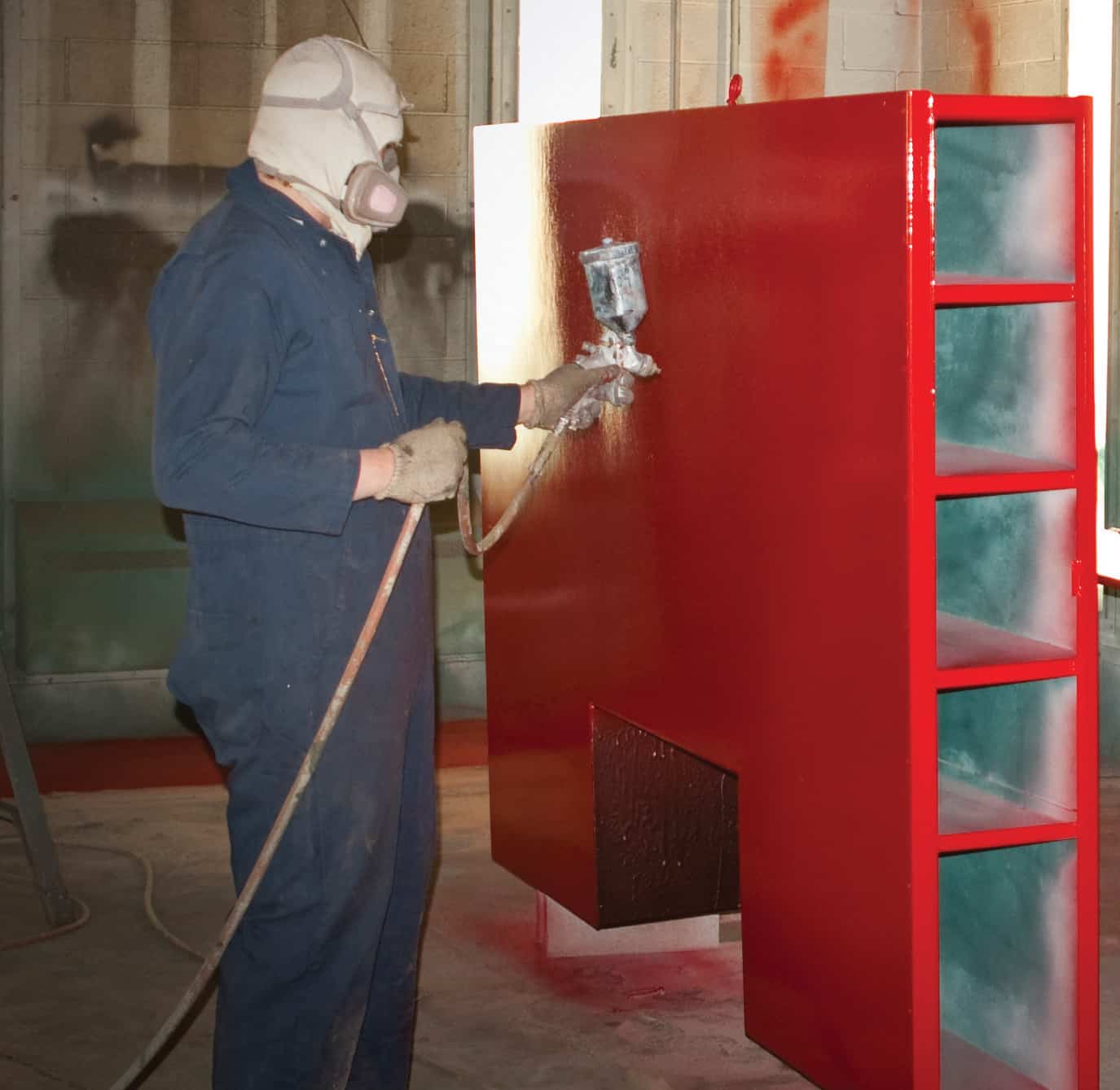 a painter wearing a protective gear painting a red shelf- what is industrial painting